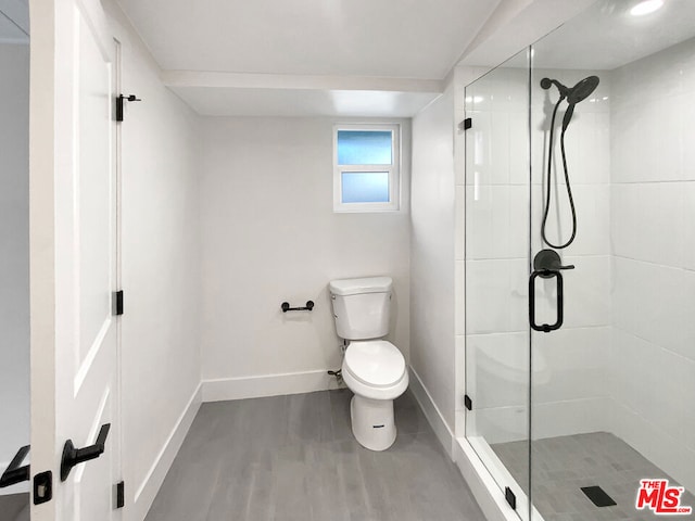 bathroom featuring toilet, a shower with shower door, and hardwood / wood-style flooring