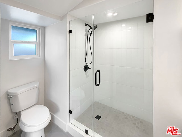 bathroom featuring a shower with door and toilet