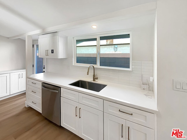 kitchen featuring dishwasher, backsplash, white cabinetry, and sink