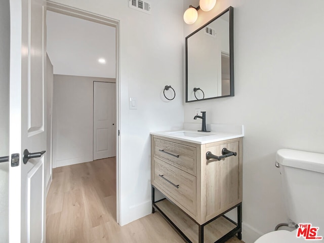 bathroom featuring toilet, vanity, and hardwood / wood-style flooring