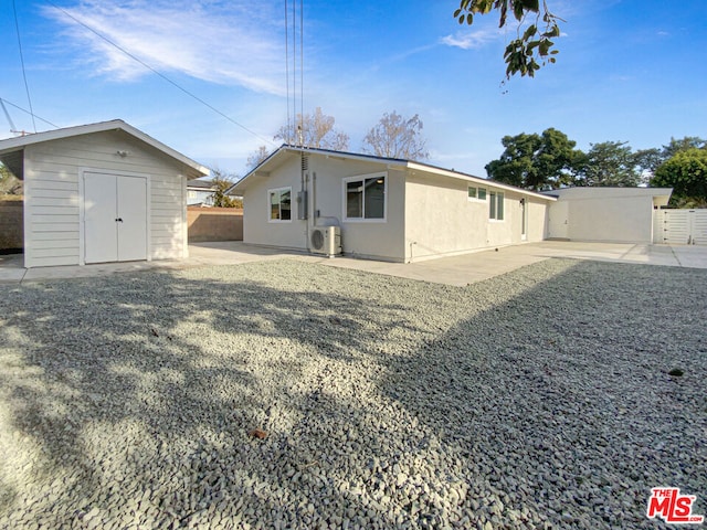 back of house with ac unit, a patio, and a storage shed