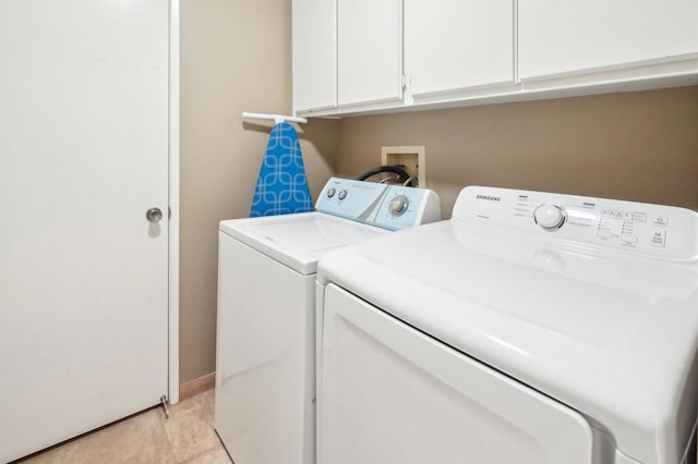 clothes washing area with cabinets and washer and dryer