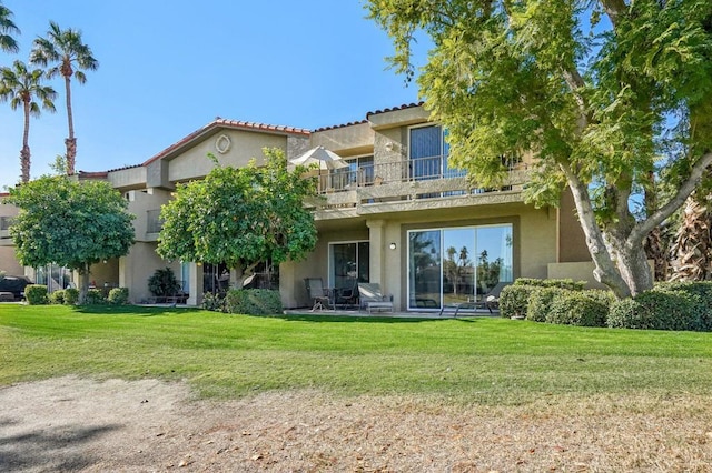 rear view of property with a lawn and a balcony