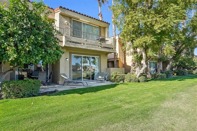 back of house with a yard, a patio, and a balcony