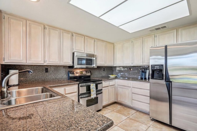 kitchen featuring sink, a skylight, light tile patterned floors, stainless steel appliances, and backsplash