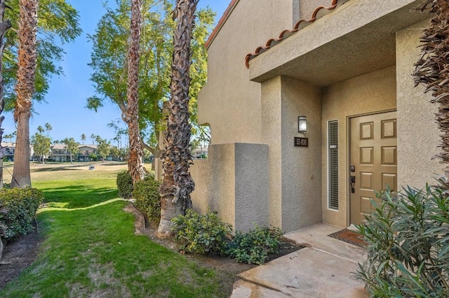 view of exterior entry featuring a lawn