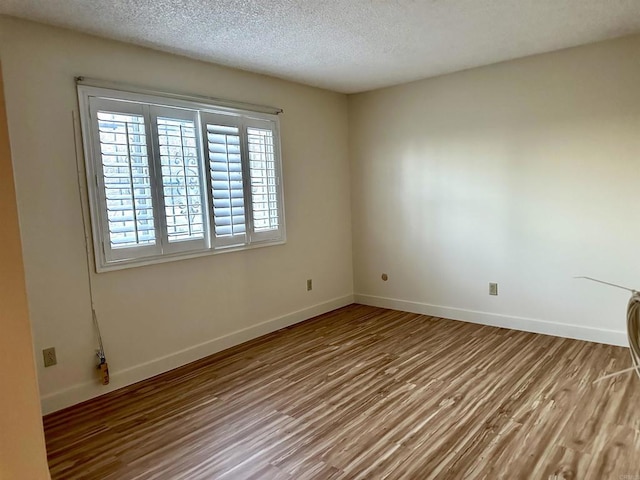 unfurnished room with wood-type flooring and a textured ceiling