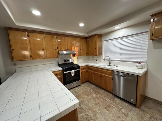 kitchen with appliances with stainless steel finishes, sink, and tile countertops