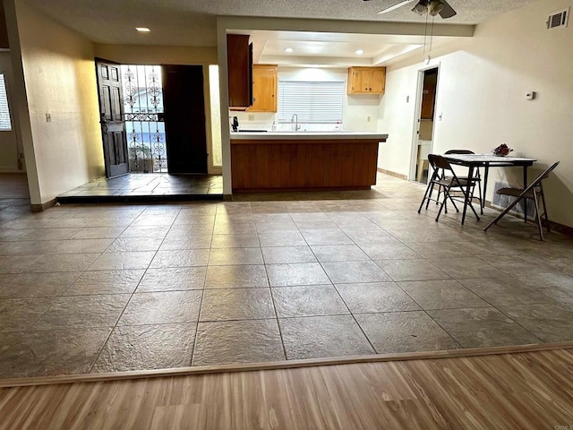 kitchen featuring ceiling fan, kitchen peninsula, sink, and wood-type flooring