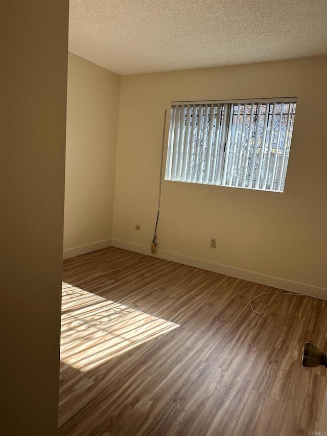 empty room with a textured ceiling and hardwood / wood-style flooring