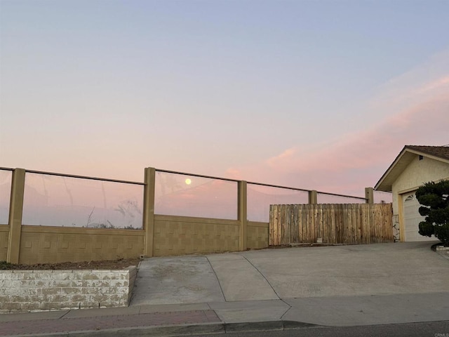 patio terrace at dusk featuring a garage