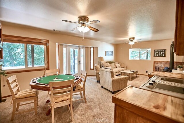 6204 Spruce Ave, Angelus Oaks, CA 92305 - recreation room with light colored carpet, ceiling fan, a wood stove, and baseboards