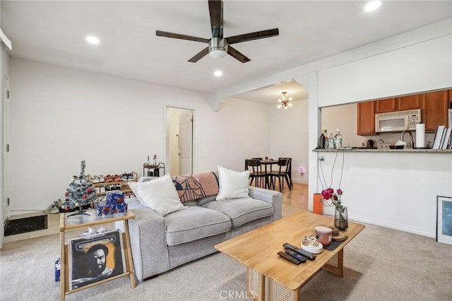 carpeted living room featuring ceiling fan with notable chandelier