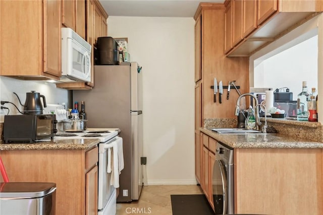 kitchen with light stone countertops, white appliances, sink, washer / dryer, and light tile patterned flooring