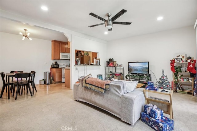 living room with light carpet and ceiling fan with notable chandelier