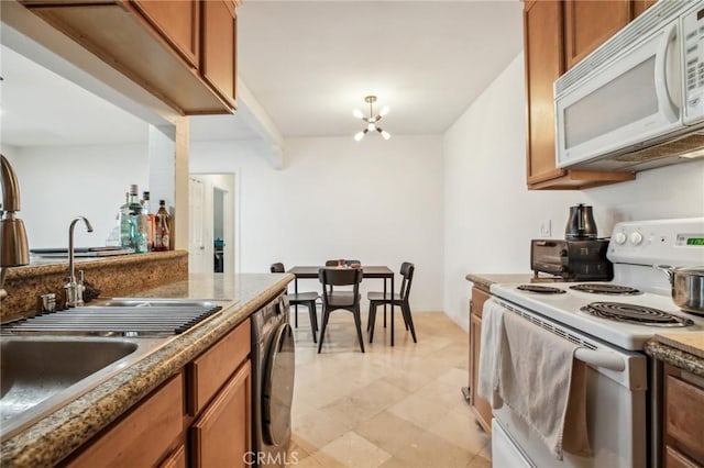 kitchen featuring white appliances, sink, dark stone counters, and a chandelier