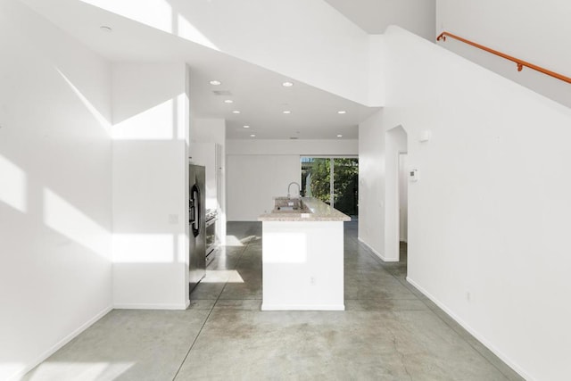 kitchen featuring a high ceiling, sink, and stainless steel fridge