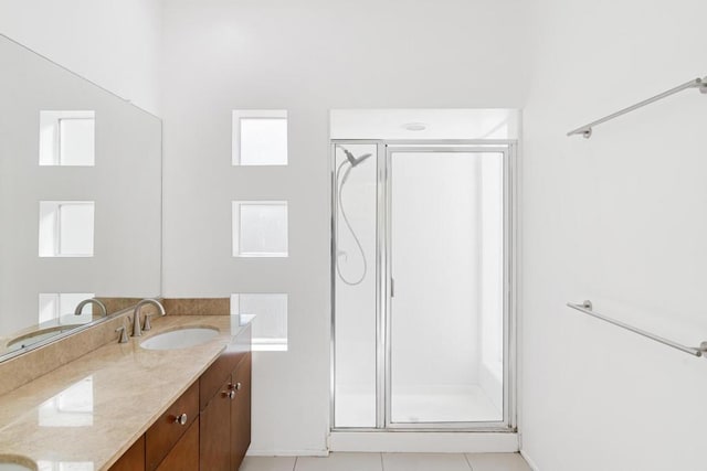 bathroom with a shower with shower door, vanity, tile patterned flooring, and a wealth of natural light