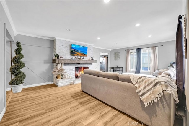 living room featuring light hardwood / wood-style floors, a brick fireplace, and crown molding