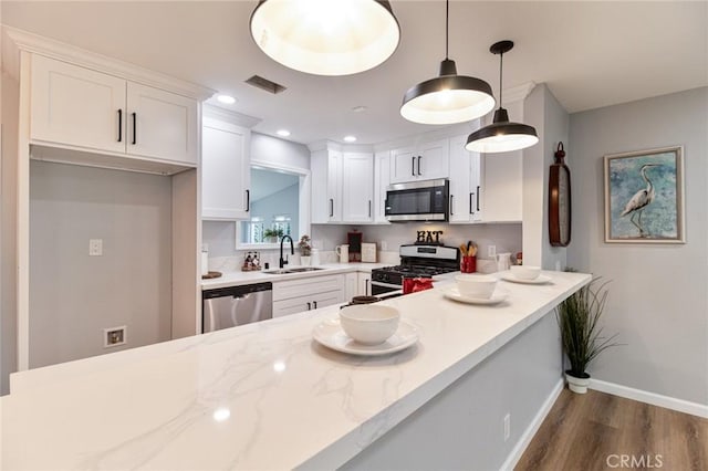 kitchen featuring pendant lighting, white cabinets, sink, dark hardwood / wood-style flooring, and stainless steel appliances