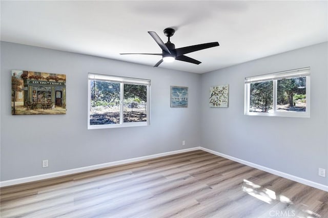 spare room featuring light wood-type flooring, ceiling fan, and a healthy amount of sunlight