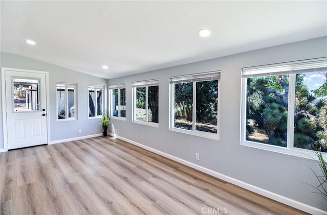 empty room featuring light hardwood / wood-style flooring, a healthy amount of sunlight, and lofted ceiling