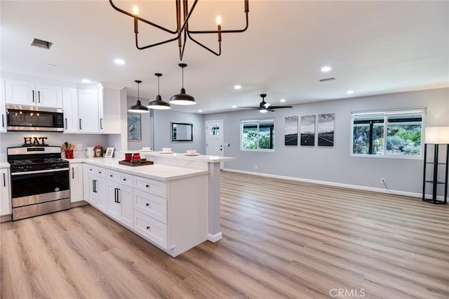 kitchen with kitchen peninsula, white cabinetry, plenty of natural light, and appliances with stainless steel finishes