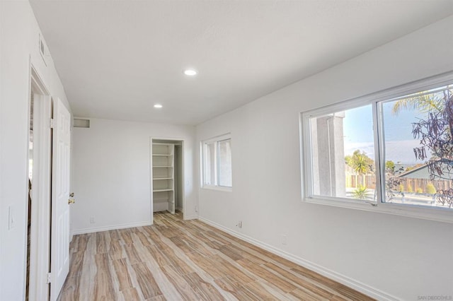 unfurnished bedroom featuring a closet, light hardwood / wood-style floors, and multiple windows