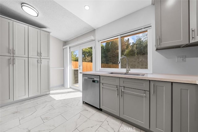 kitchen featuring stainless steel dishwasher, sink, gray cabinets, and a textured ceiling