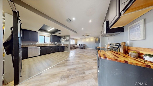 kitchen with dishwasher, butcher block countertops, light hardwood / wood-style floors, a raised ceiling, and sink