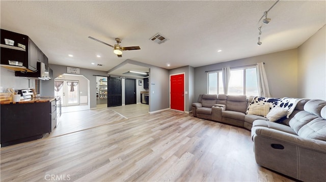 living room featuring a textured ceiling, light hardwood / wood-style floors, and ceiling fan