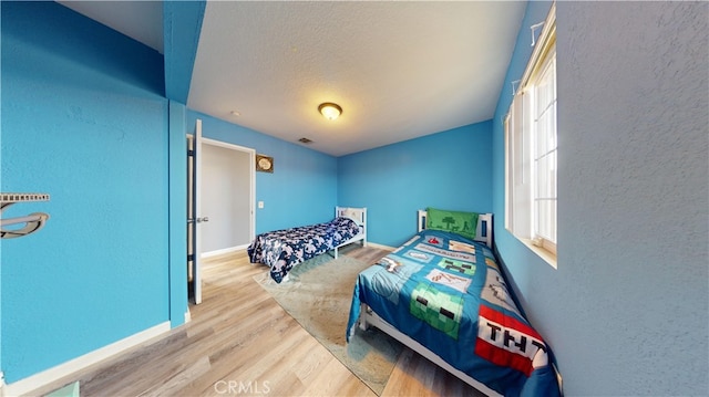 bedroom featuring light hardwood / wood-style floors and a textured ceiling