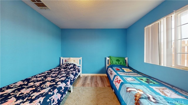 bedroom with multiple windows, light hardwood / wood-style flooring, and a textured ceiling