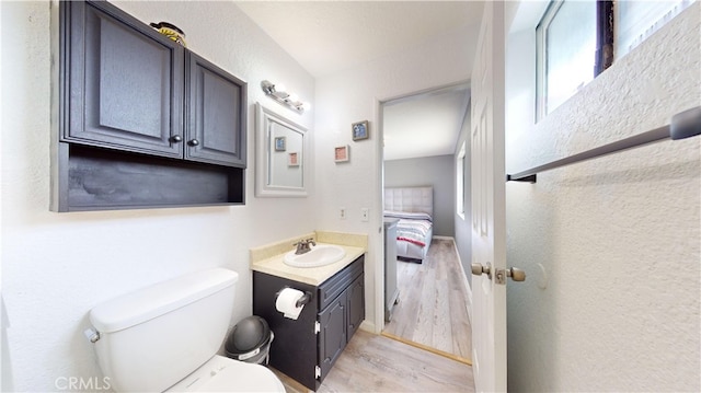 bathroom with hardwood / wood-style flooring, plenty of natural light, vanity, and toilet