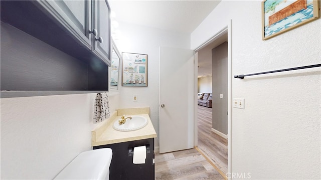 bathroom with hardwood / wood-style floors, vanity, and toilet