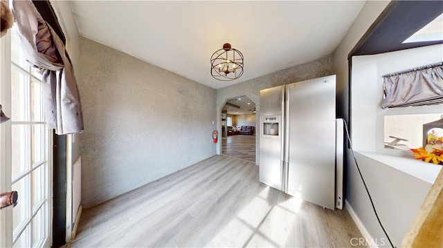 kitchen with stainless steel fridge, an inviting chandelier, and light hardwood / wood-style flooring