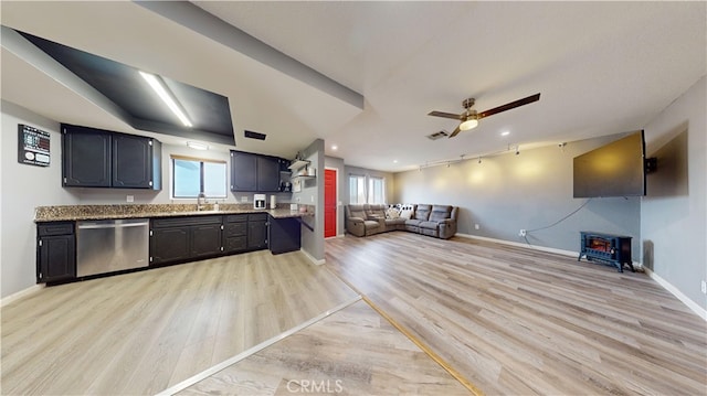 kitchen with stainless steel dishwasher, light hardwood / wood-style floors, a wood stove, and a wealth of natural light