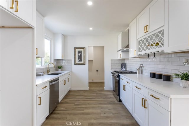 kitchen featuring hardwood / wood-style floors, white cabinets, sink, decorative backsplash, and appliances with stainless steel finishes