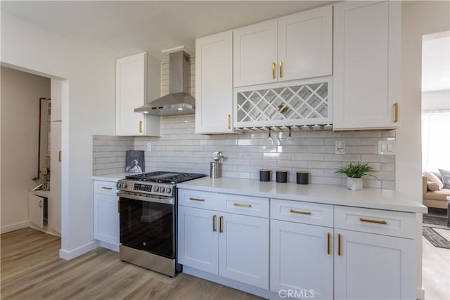 kitchen featuring gas range, white cabinetry, and wall chimney exhaust hood