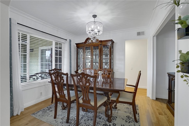 dining area featuring light wood-type flooring, crown molding, and a chandelier