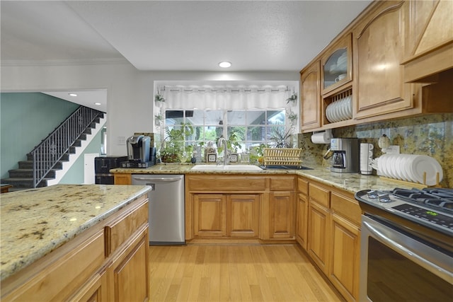 kitchen with tasteful backsplash, ornamental molding, stainless steel appliances, sink, and light hardwood / wood-style flooring