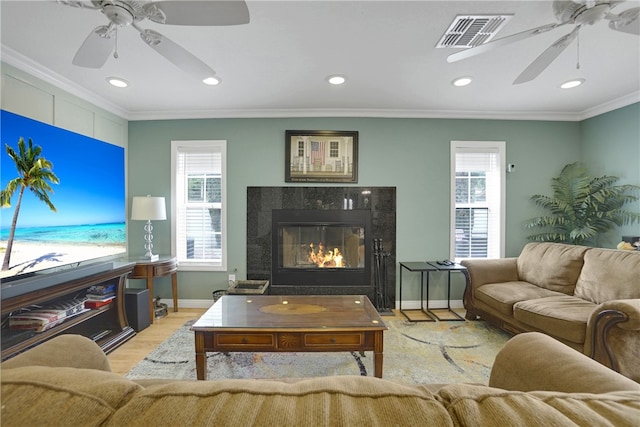 living room with crown molding, light hardwood / wood-style flooring, and a high end fireplace