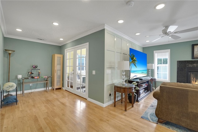 living room with ceiling fan, plenty of natural light, light wood-type flooring, and crown molding