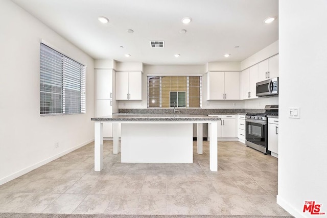 kitchen with a breakfast bar, appliances with stainless steel finishes, a center island, and white cabinetry