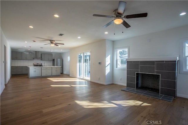 unfurnished living room with hardwood / wood-style flooring, ceiling fan, and a fireplace