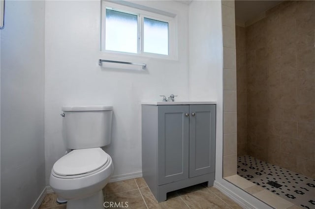 bathroom with tile patterned flooring, a tile shower, vanity, and toilet