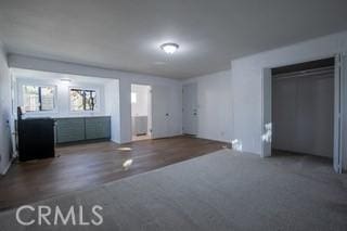 unfurnished bedroom with multiple windows, a closet, and dark hardwood / wood-style floors