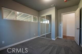 unfurnished bedroom with a closet and dark carpet