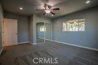 unfurnished bedroom with ceiling fan, a closet, and dark carpet