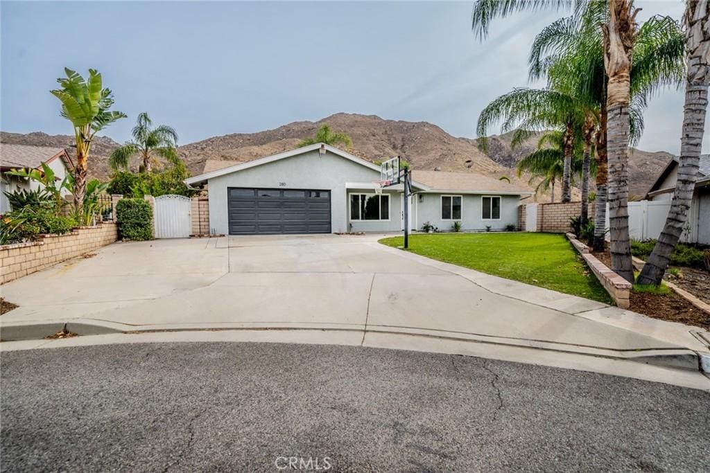 ranch-style home featuring a mountain view, a garage, and a front lawn